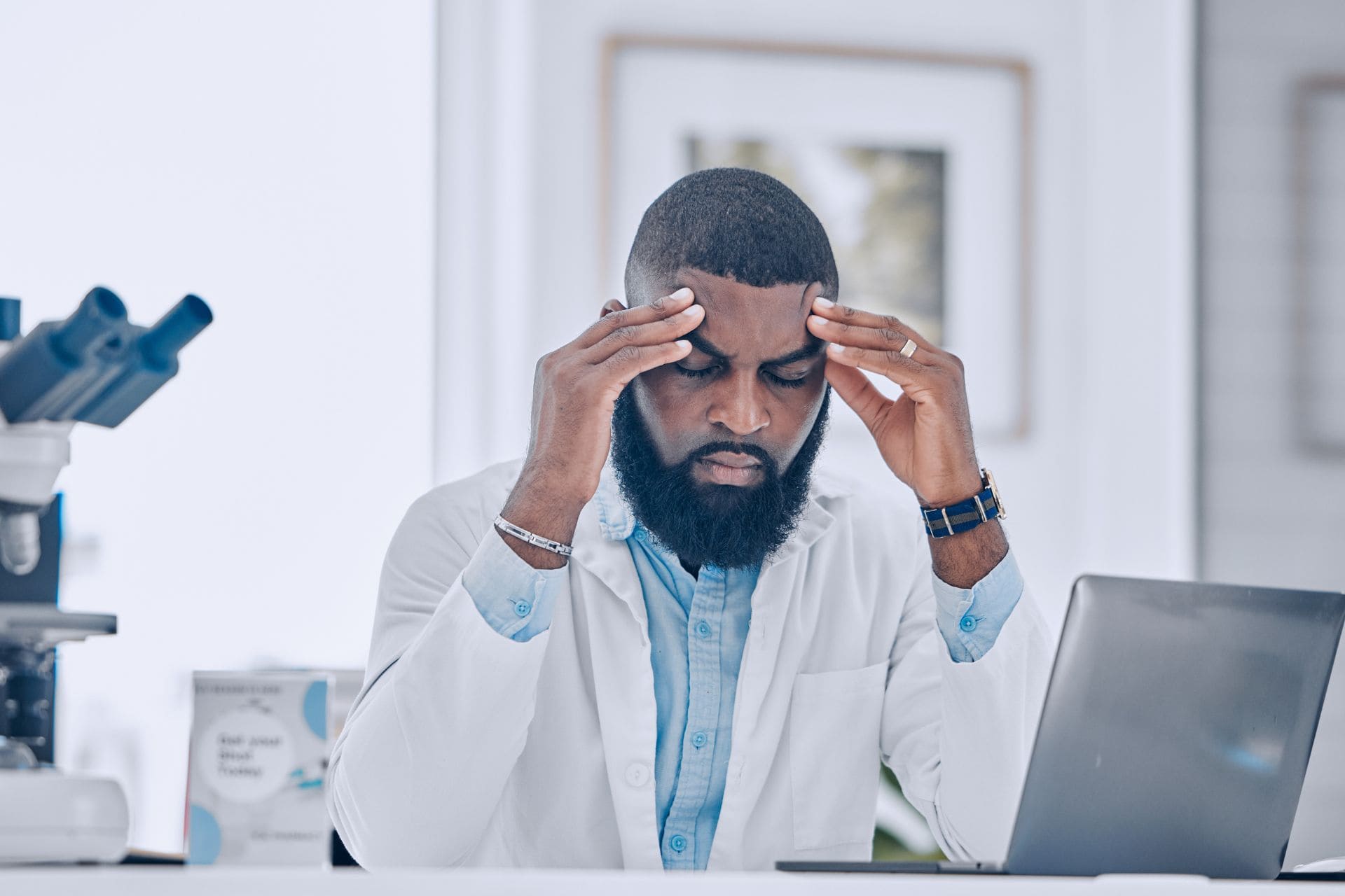 Hombre en un entorno profesional sufriendo un fuerte dolor de cabeza, ejemplificando el uso de CBD para la migraña en la vida diaria.