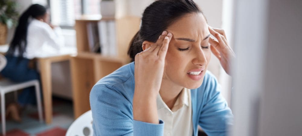 Mujer con expresión de dolor intenso presionando sus sienes, ilustrando la necesidad de alivio con CBD para la migraña.