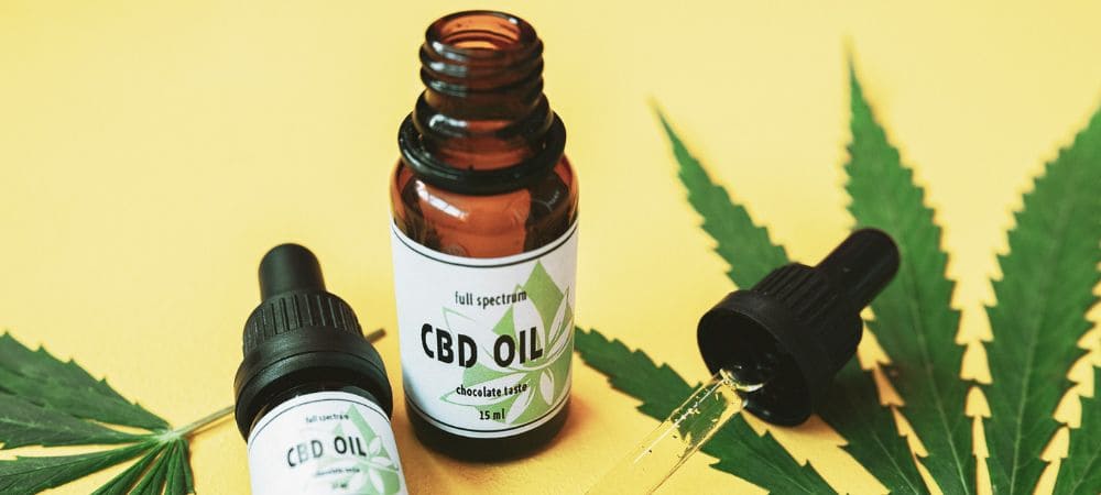 Aceite de CBD de espectro completo con gotero y hojas de cannabis, imagen representativa de los efectos del CBD en el bienestar diario