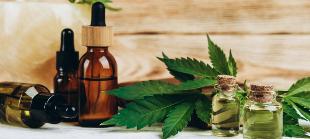 Diferentes formatos de aceite de CBD con hojas de cannabis, imagen ilustrativa de los efectos del CBD y su uso cotidiano