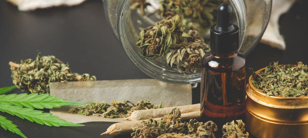 Flores de CBD, aceite de cannabidiol y porros de cannabis sin THC sobre una mesa