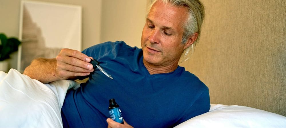Hombre usando melatonina con cbd en aceite antes de dormir en la cama